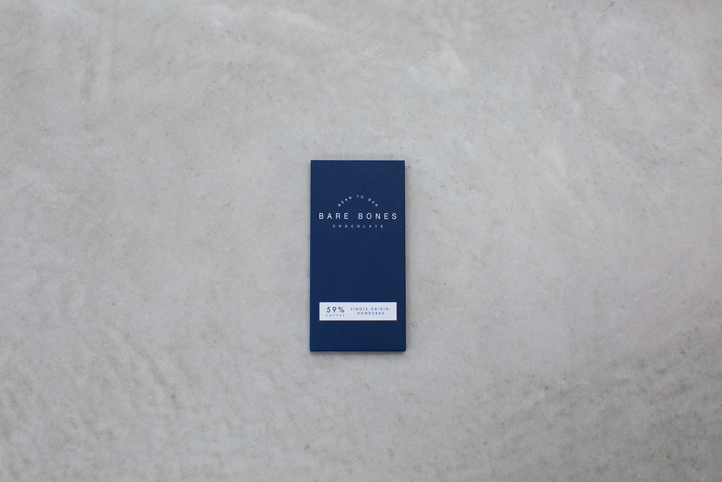 Blue chocolate bar packaging with 'Bare Bones' branding on a gray surface