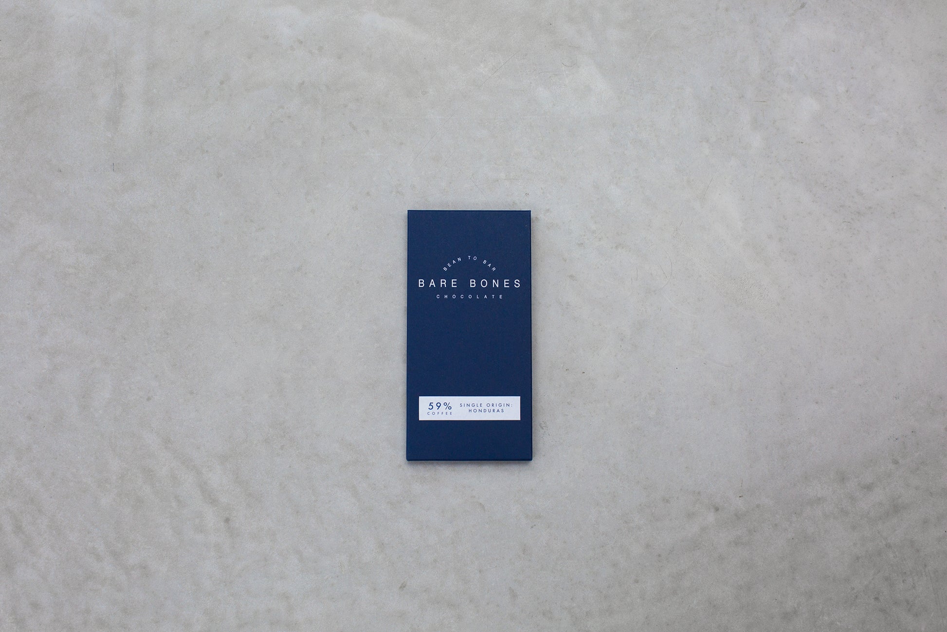 Blue chocolate bar packaging with 'Bare Bones' branding on a gray surface